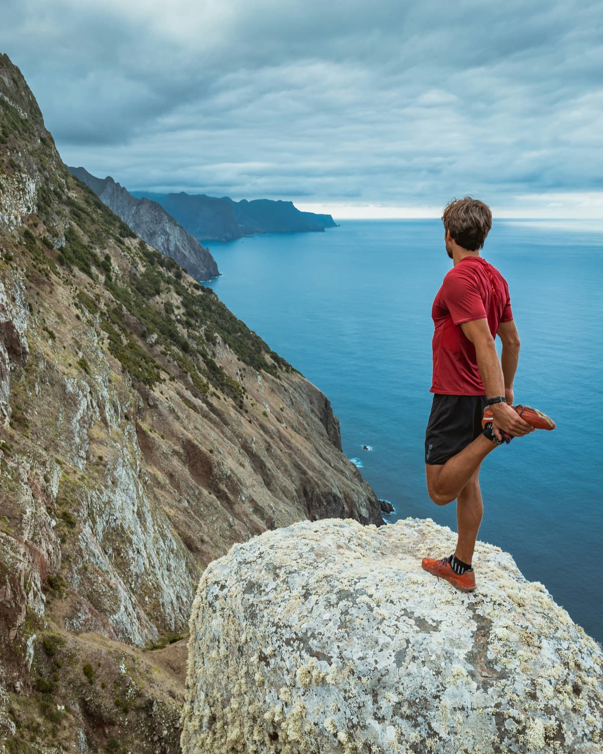 Runner stretching on cliff overlooking ocean